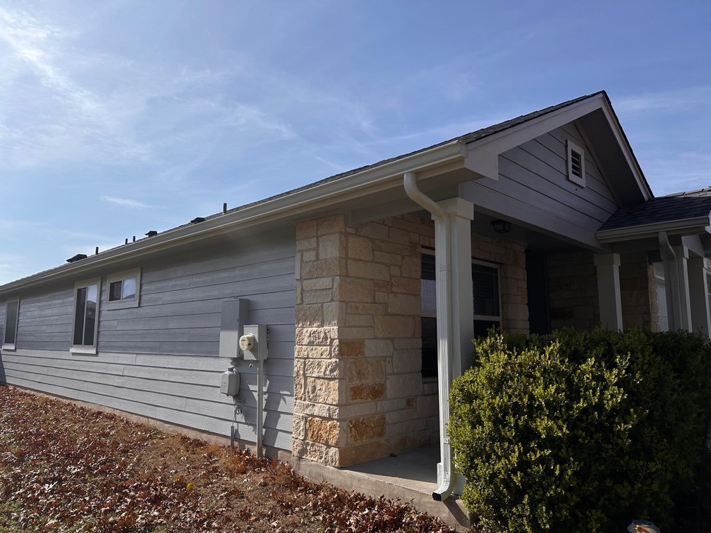 Same Hutto, TX home after exterior repainting in cool gray with white trim, alongside limestone masonry