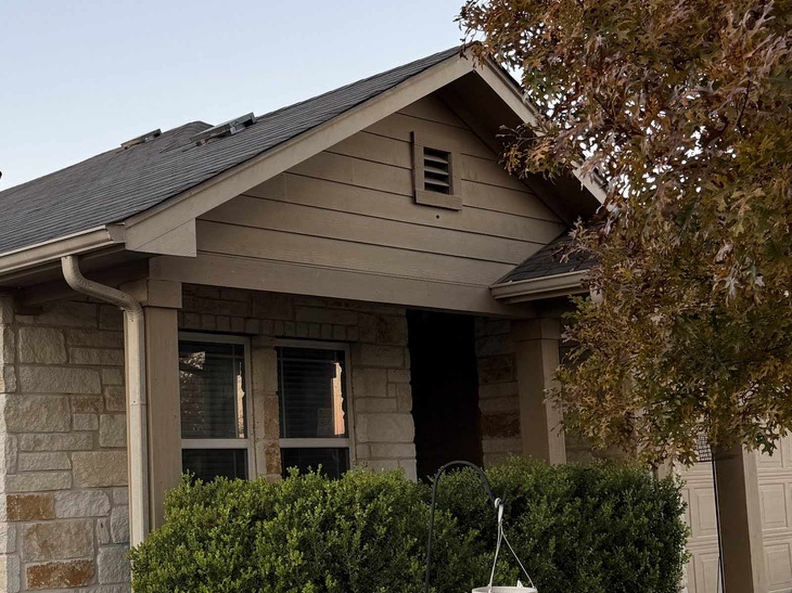 Tan and brown exterior paint on a Hutto, TX home before repainting, showing original siding, gable trim, and fascia color